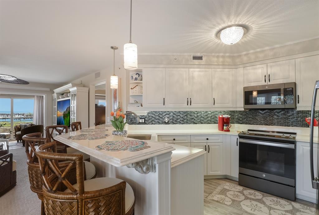 A kitchen with white cabinets, a breakfast bar, and a view of the water outside — 5856 GASPARILLA ROAD UNIT M31, BOCA GRANDE, FL