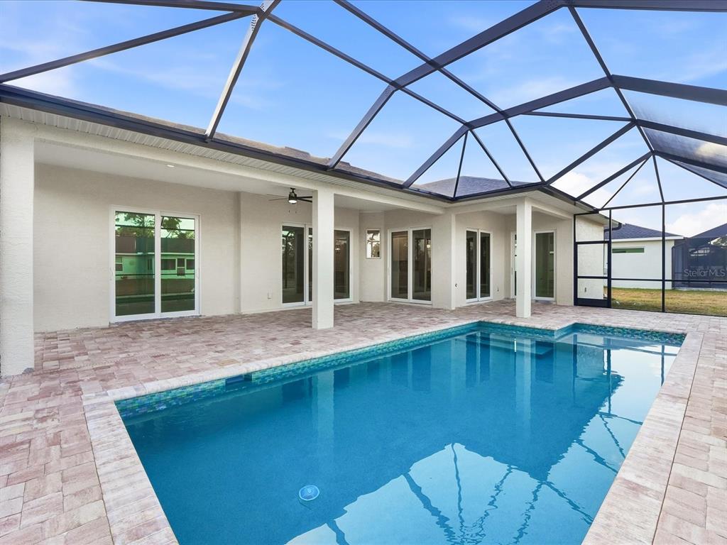 A rectangular swimming pool sits on a paved patio enclosed by a large screen cage — 13364 RAYBURN LANE, PORT CHARLOTTE, FL