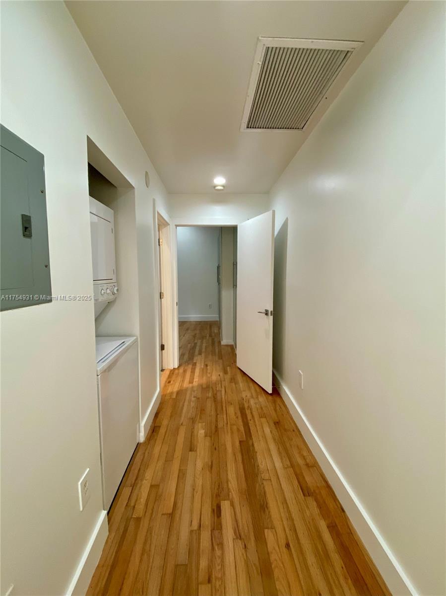 A hallway features hardwood floors, a stacked washer and dryer, and a white interior door — 929 Michigan Ave # 5, Miami Beach FL 33139, MIAMI BEACH, FL