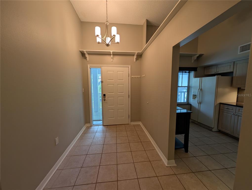 An entryway with tile flooring and a white front door leads into a kitchen area — 2577 DOLLY BAY DRIVE UNIT 302, PALM HARBOR, FL