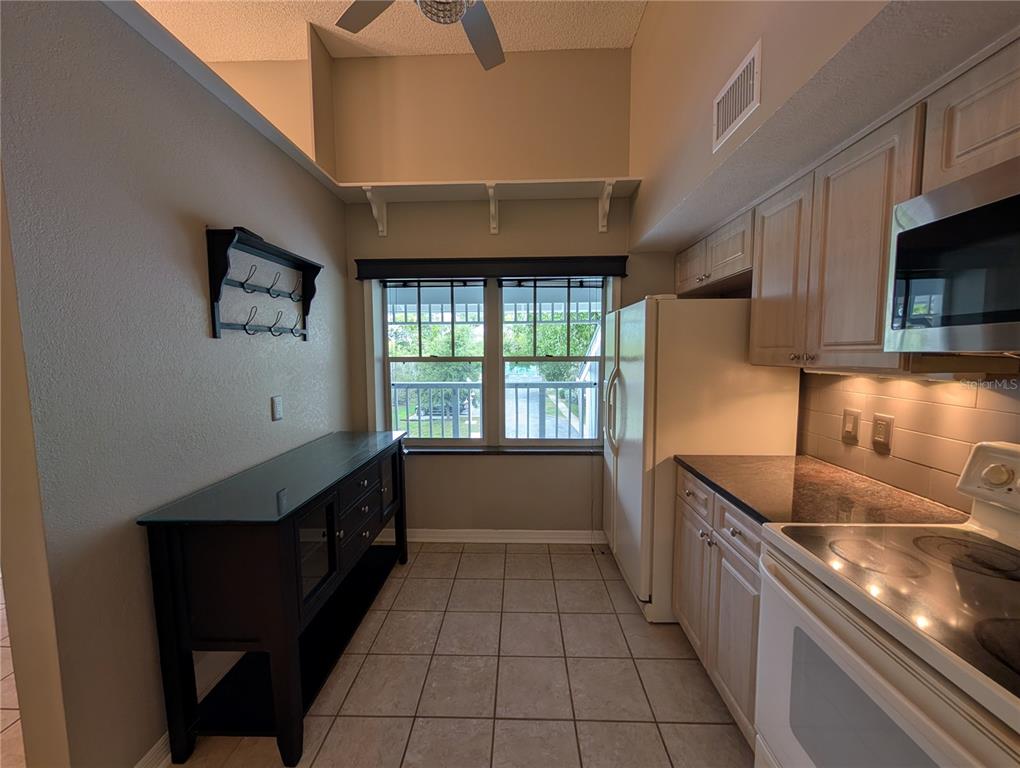 A kitchen features light wood cabinets, dark countertops, a white refrigerator, and a black sideboard — 2577 DOLLY BAY DRIVE UNIT 302, PALM HARBOR, FL