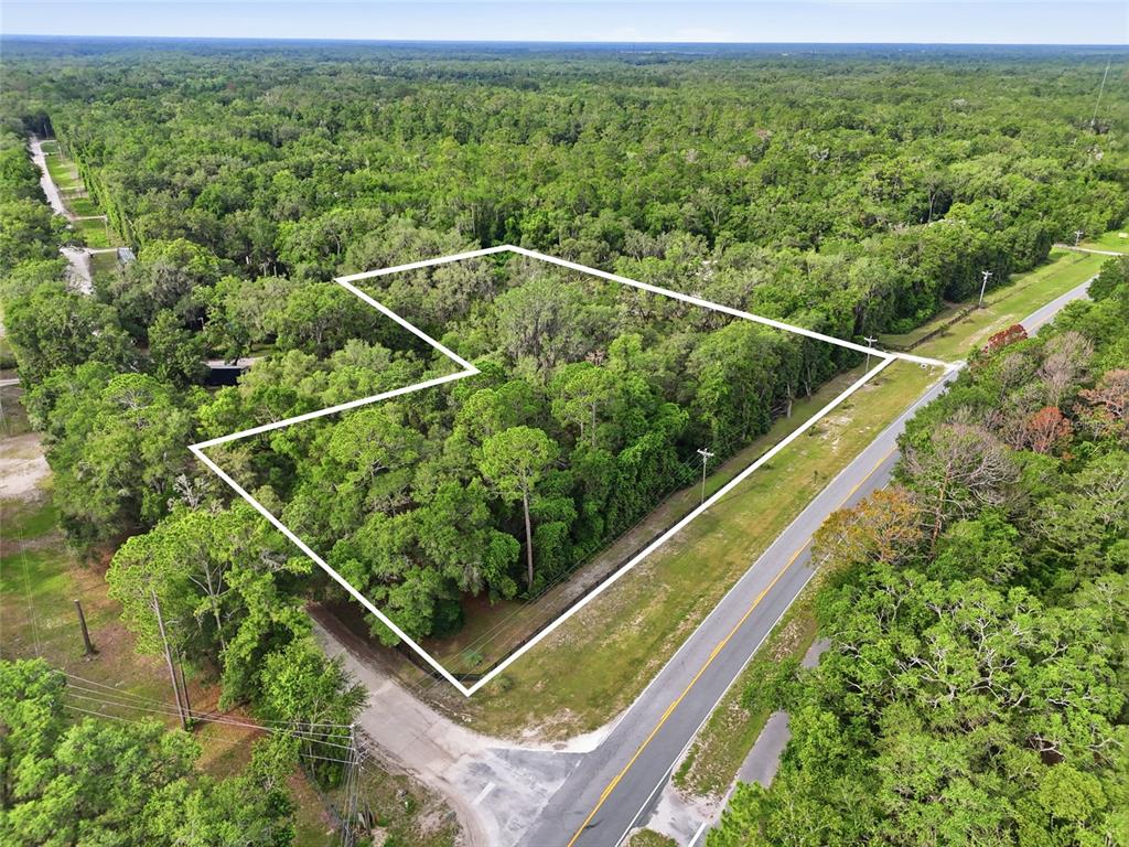 An aerial view shows a wooded, L-shaped plot of land bordered by two roads — 00 SW COUNTY ROAD 18, FORT WHITE, FL