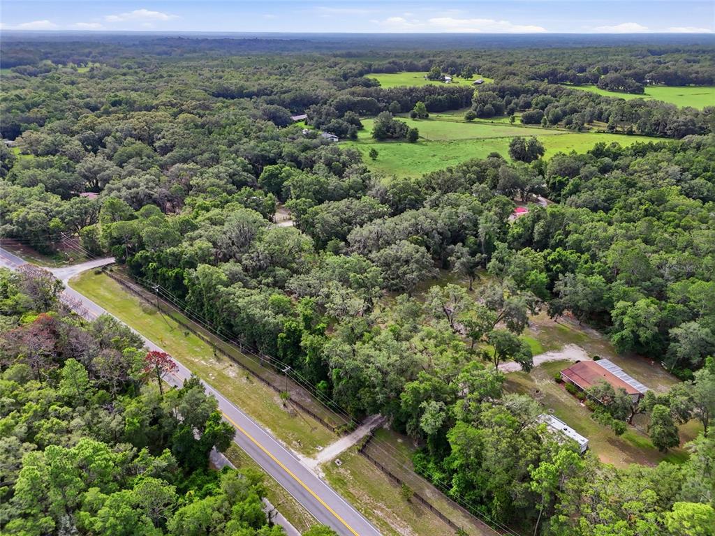 An aerial view shows a rural road bordering a wooded lot with a small house — 00 SW COUNTY ROAD 18, FORT WHITE, FL