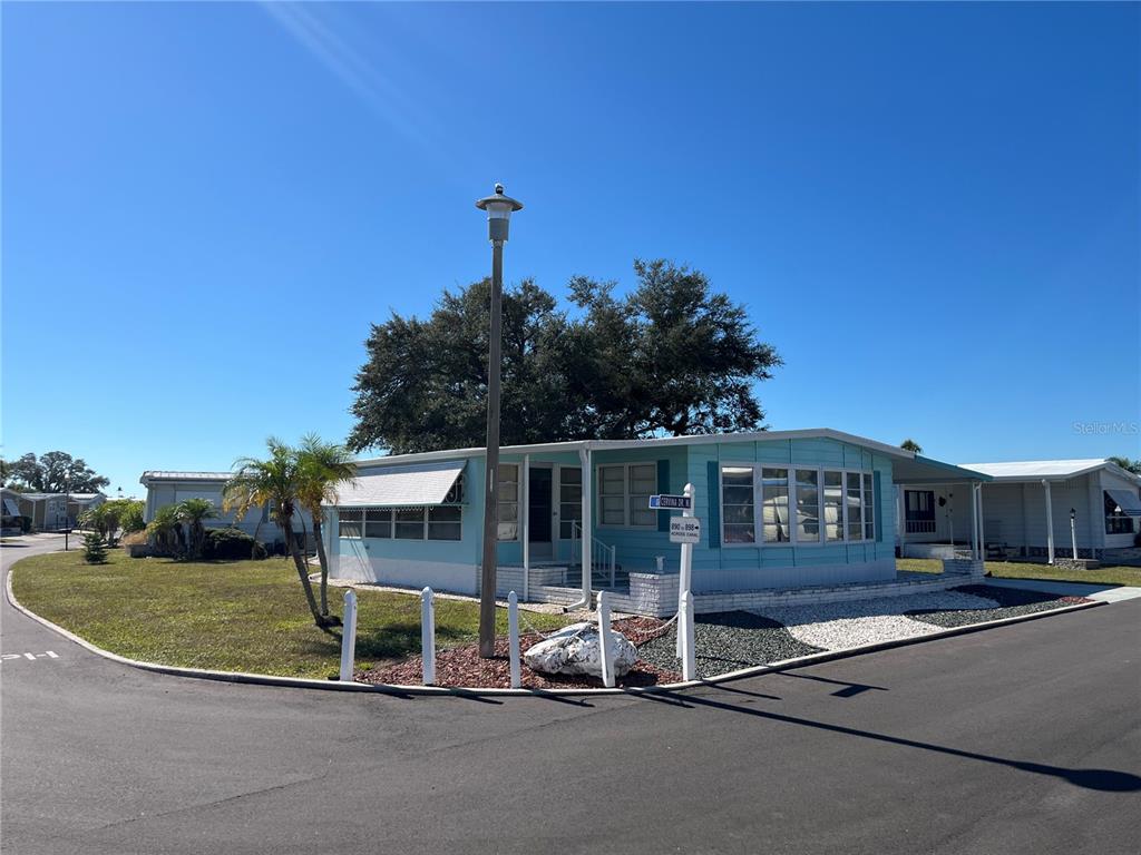 A light blue mobile home sits on a corner lot with a street lamp nearby — 518 CERVINA DRIVE N, VENICE, FL