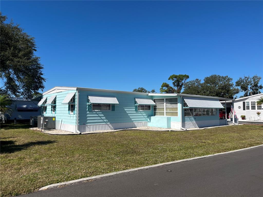A light blue manufactured home with white awnings sits on a grassy lot — 518 CERVINA DRIVE N, VENICE, FL