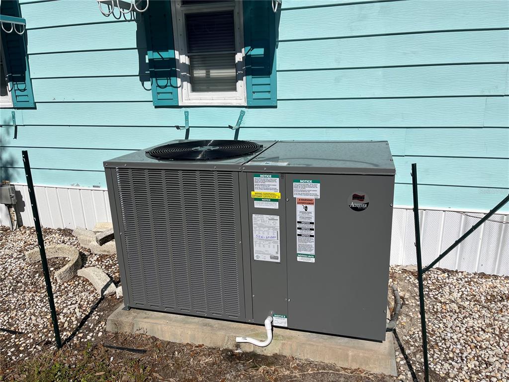 A gray HVAC unit sits on a concrete pad against a light blue house exterior — 518 CERVINA DRIVE N, VENICE, FL