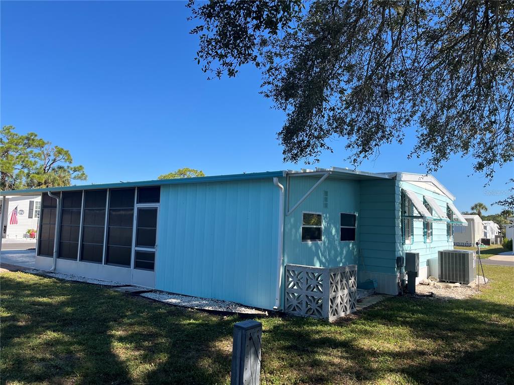 A light blue mobile home features a screened-in porch and a lattice-enclosed foundation — 518 CERVINA DRIVE N, VENICE, FL