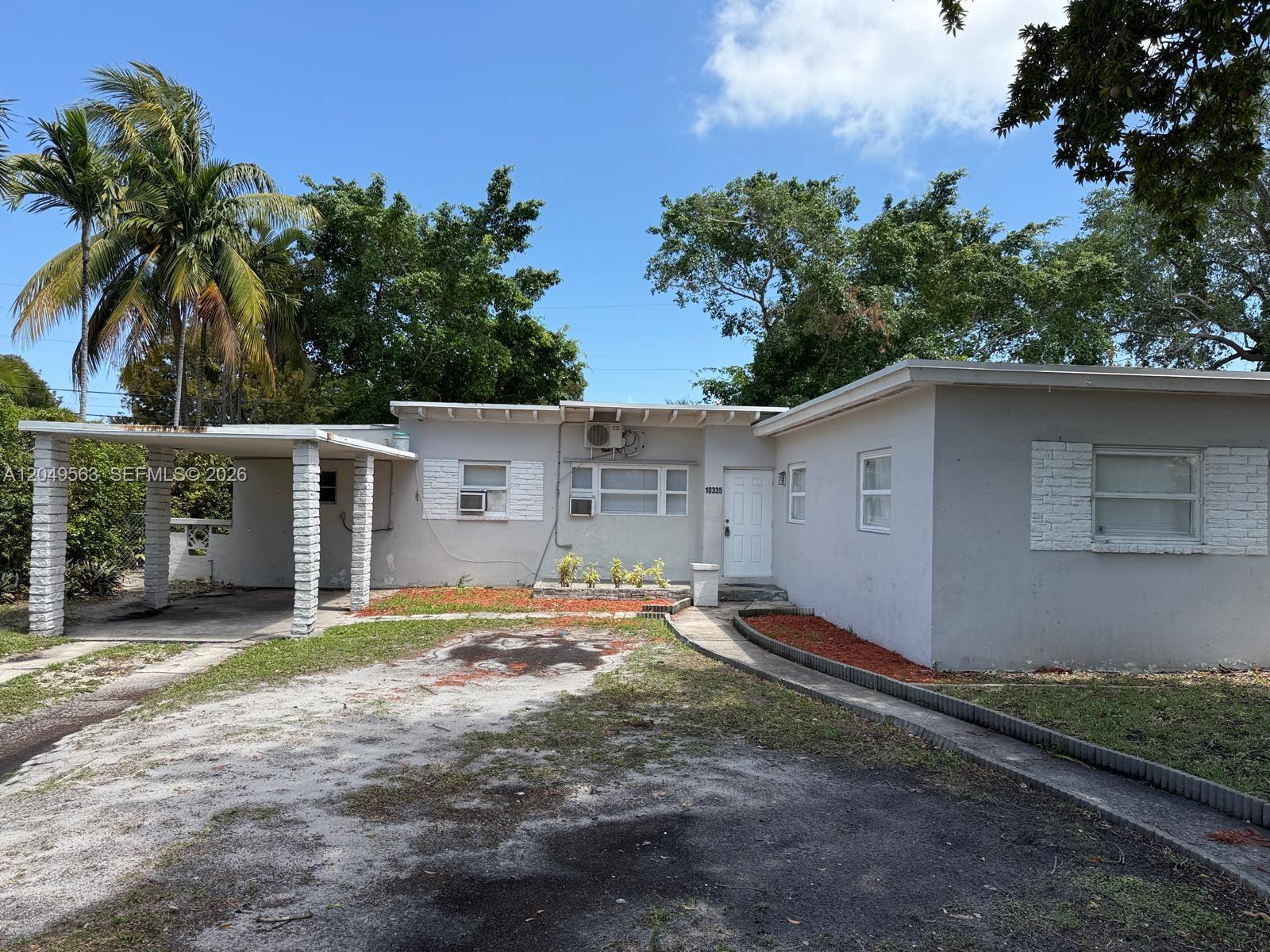 A single-story house with a carport, white exterior walls, and a gravel driveway — 10335 NW 2nd Ct # 1, Miami FL 33150, MIAMI, FL