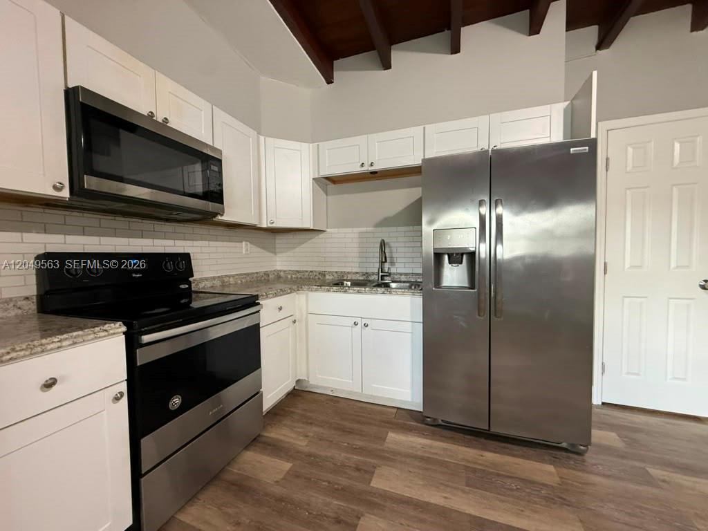 A kitchen features white cabinets, stainless steel appliances, a subway tile backsplash, and wood flooring — 10335 NW 2nd Ct # 1, Miami FL 33150, MIAMI, FL