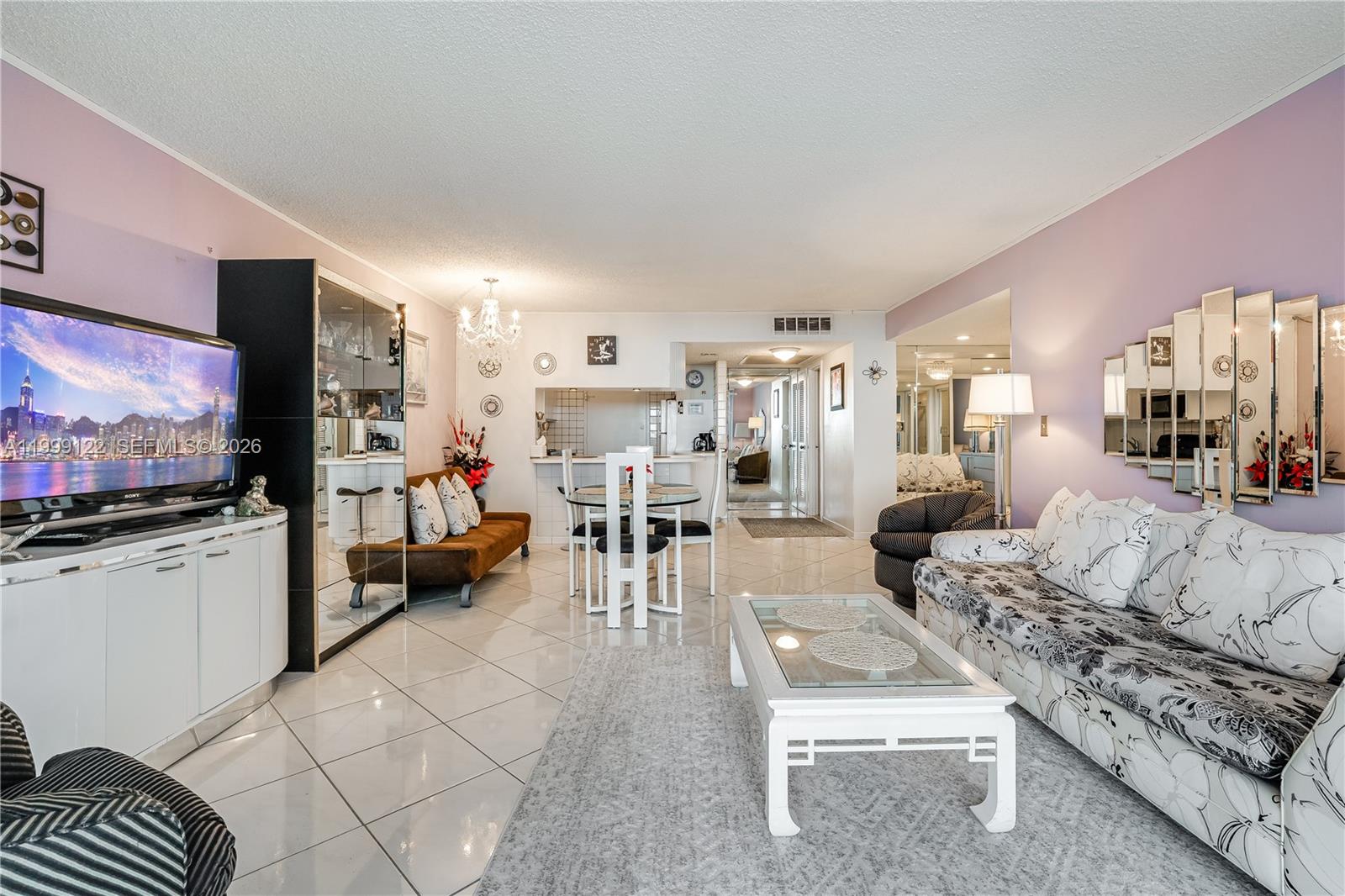 A living and dining area features white tile floors, a patterned sofa, and mirrored wall accents — 2030 S Ocean Dr # 1903, Hallandale Beach FL 33009, HALLANDALE BEACH, FL