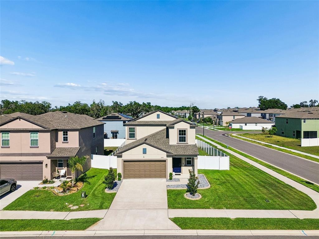 An aerial view shows a two-story suburban house with a tan exterior and attached garage — 6450 BACK FORTY LOOP, ZEPHYRHILLS, FL