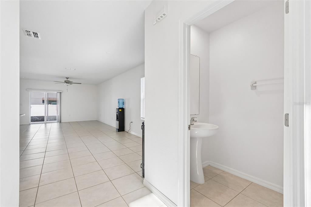 A view from a doorway into a tiled living area with a pedestal sink nearby — 6450 BACK FORTY LOOP, ZEPHYRHILLS, FL