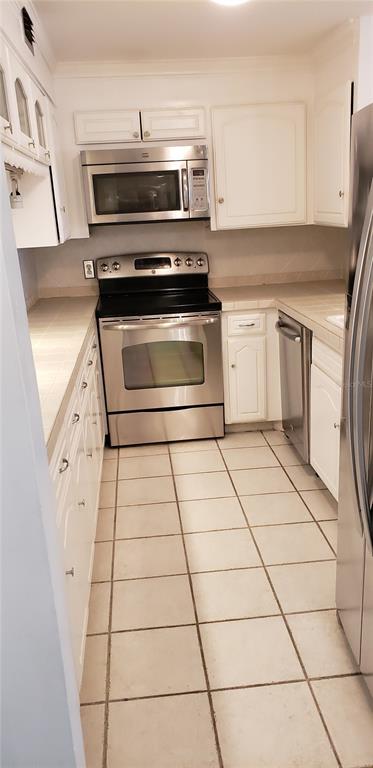 A galley kitchen features white cabinets, stainless steel appliances, and light-colored tiled flooring — 4141 BAYSHORE BOULEVARD S UNIT 1502, TAMPA, FL