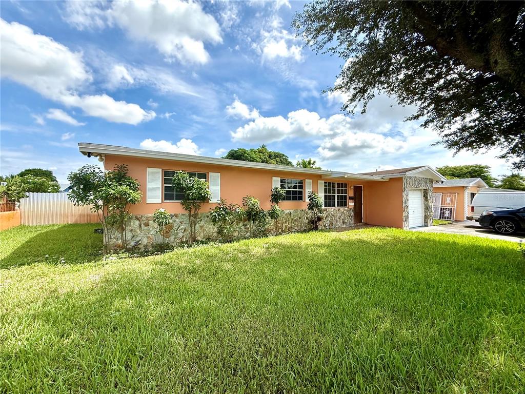 A single-story peach-colored house with stone veneer siding and a front-facing garage — 2241 NW 190TH TERRACE, MIAMI GARDENS, FL