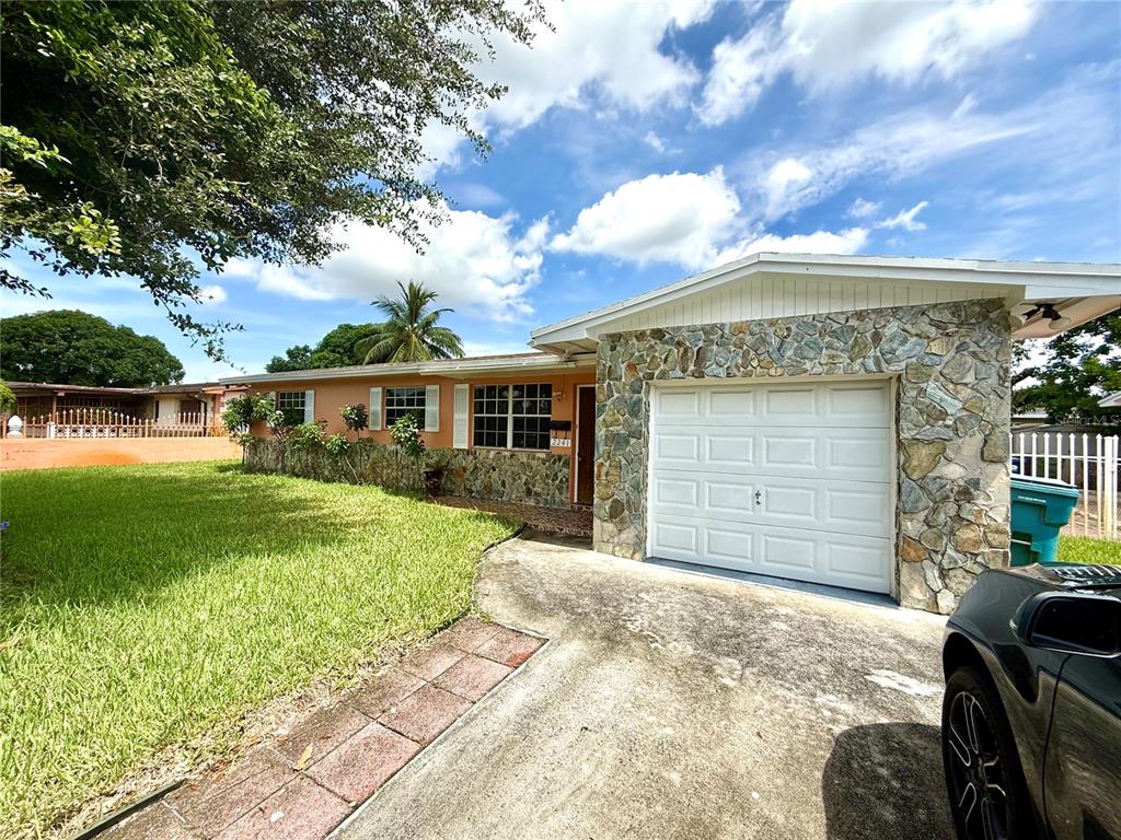 A single-story house with a stone facade, white garage door, and a concrete driveway — 2241 NW 190TH TERRACE, MIAMI GARDENS, FL