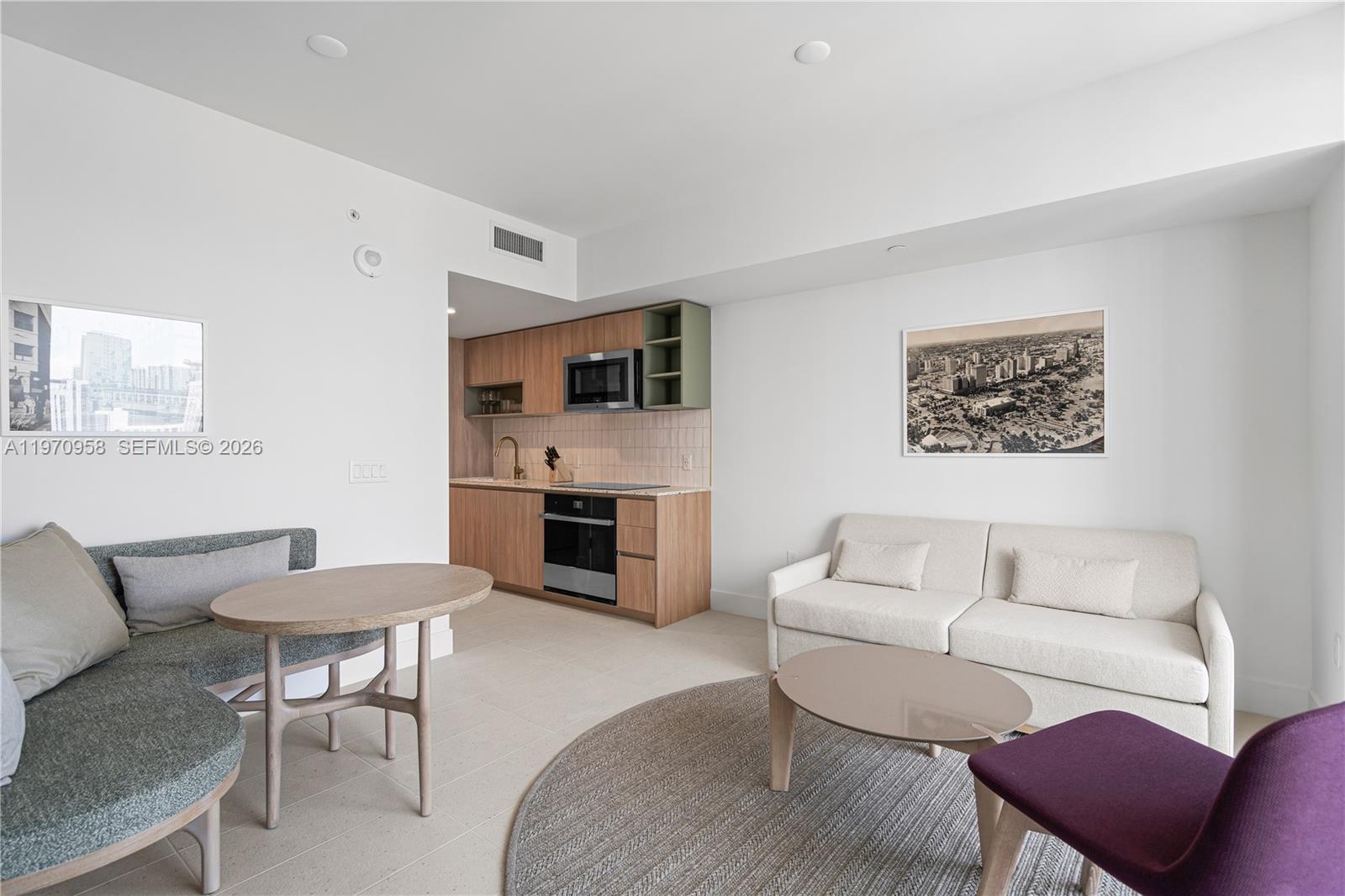 A studio apartment features a kitchenette with wood cabinets, a sofa, and a dining area — 159 NE 6th St # 2707, Miami FL 33132, MIAMI, FL