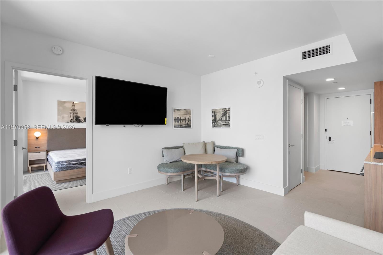 A living area features a corner banquette, a round table, and a wall-mounted television — 159 NE 6th St # 2707, Miami FL 33132, MIAMI, FL