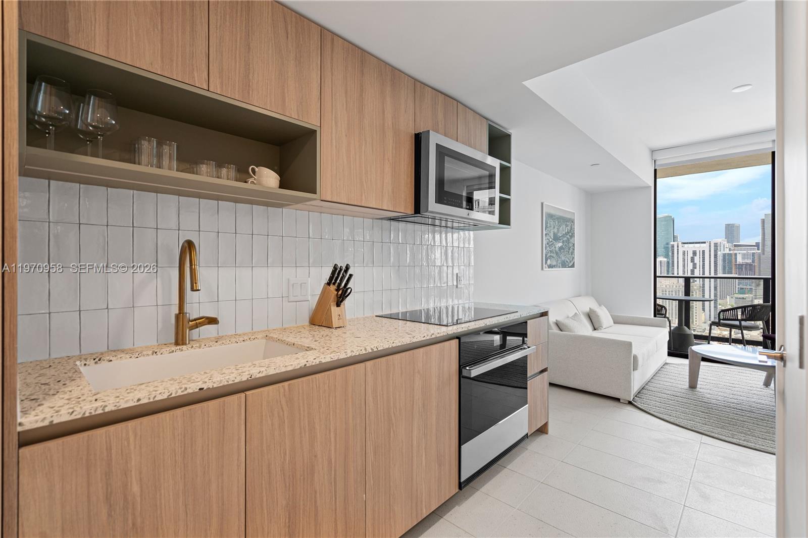 A modern kitchen features light wood cabinets, a speckled countertop, and a white tiled backsplash — 159 NE 6th St # 2707, Miami FL 33132, MIAMI, FL