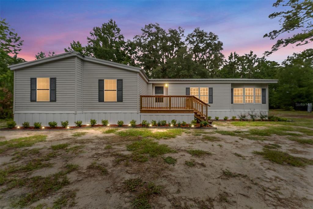 A single-story manufactured home with light gray siding and a wooden front deck — 6028 SW 91ST PLACE, LAKE BUTLER, FL