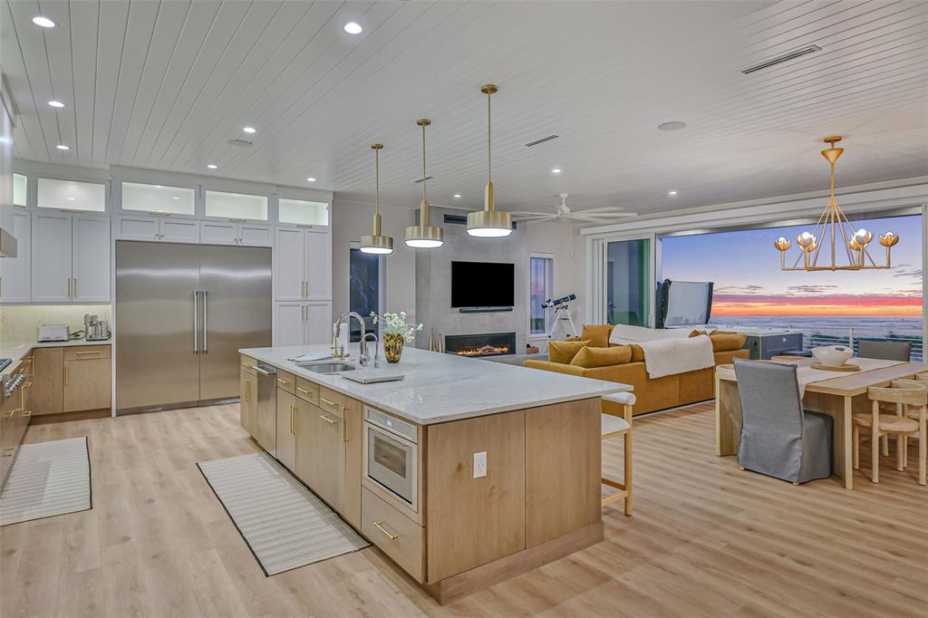 A modern kitchen with light wood cabinets and a marble island overlooks a sunset ocean view — 2214 N CENTRAL AVENUE, FLAGLER BEACH, FL