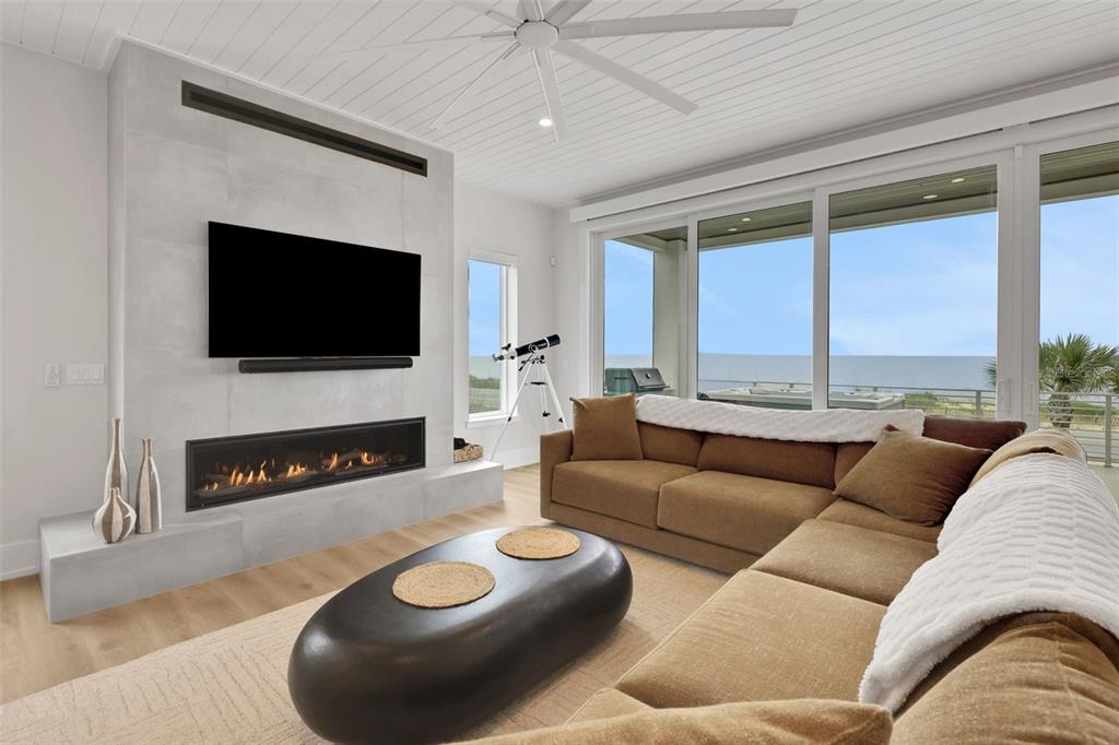 A living room features a fireplace, wall-mounted television, sectional sofa, and floor-to-ceiling windows — 2214 N CENTRAL AVENUE, FLAGLER BEACH, FL