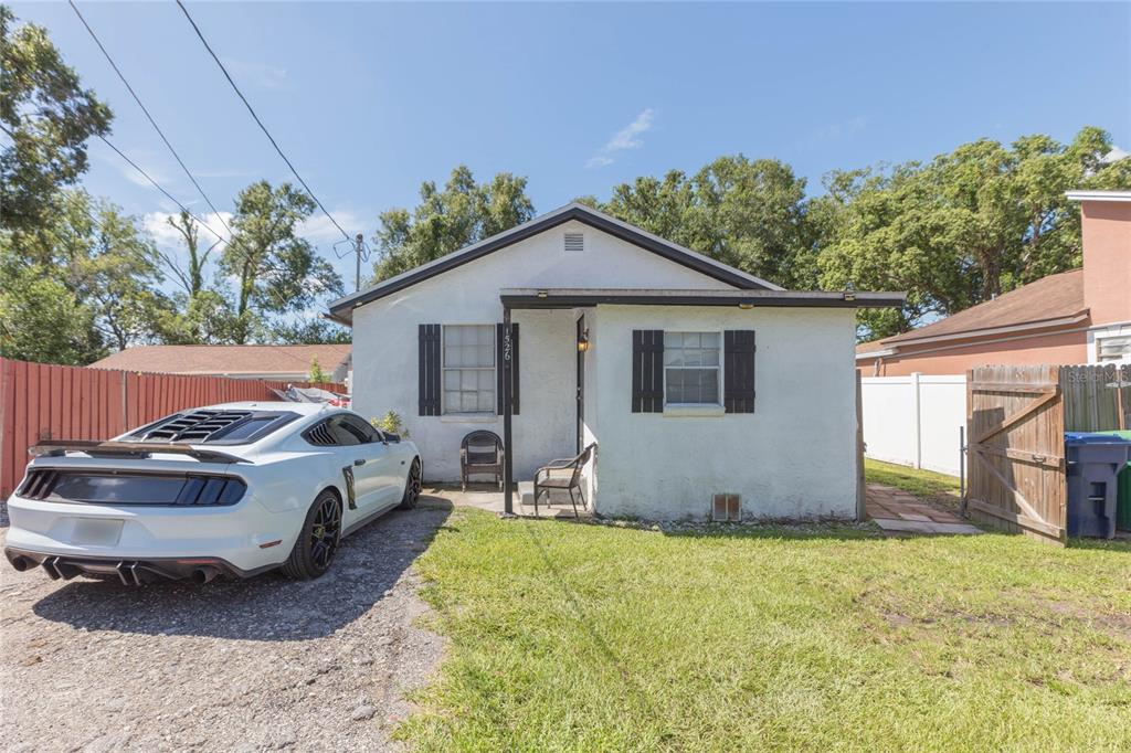 A white single-story house with a gravel driveway and a parked sports car — 1526 CLINTON, TAMPA, FL