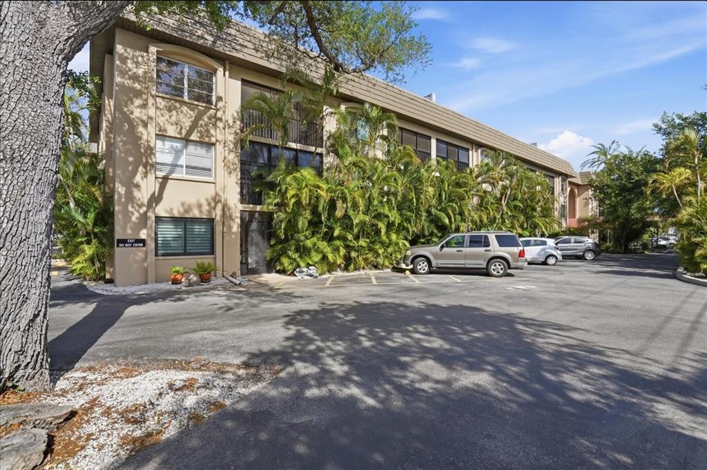 A multi-story apartment building with a parking lot and lush landscaping in front — 3700 S OSPREY AVENUE UNIT 115, SARASOTA, FL