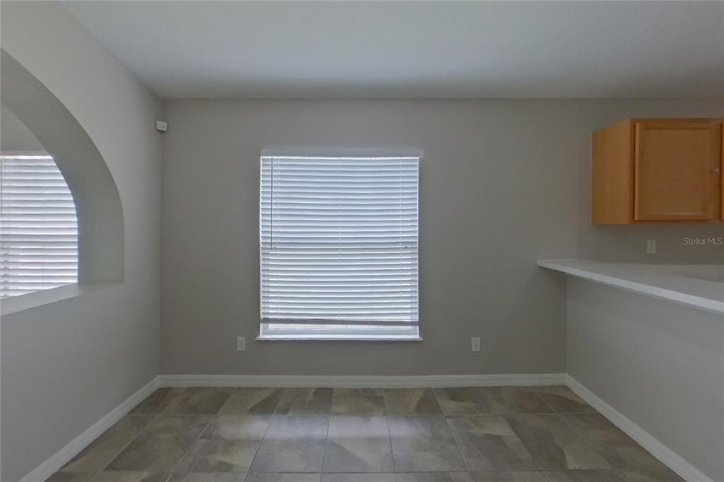 A dining area features tile flooring, a central window with blinds, and an arched wall opening — 302 ANORAK STREET, GROVELAND, FL
