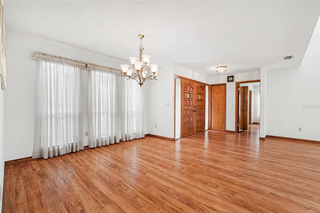 A dining room with wood-look flooring, a chandelier, and a double-door entryway — 34334 WHISPERING OAKS BOULEVARD, DADE CITY, FL
