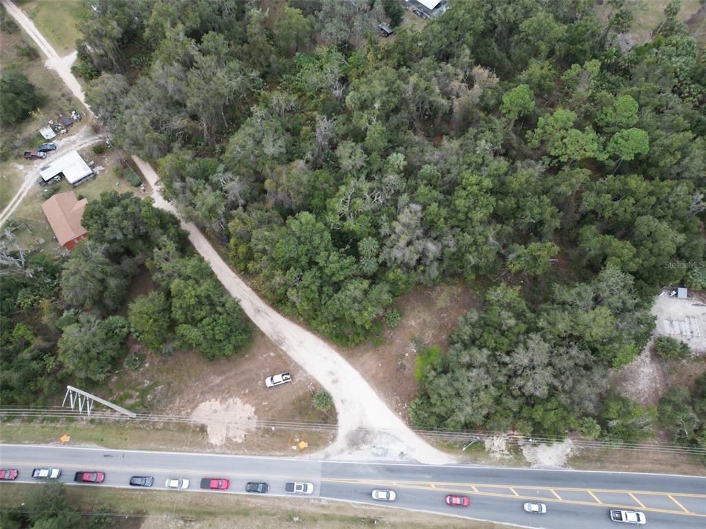 An aerial view shows a wooded lot with a dirt driveway leading from a road — 9915 COUNTY ROAD 44, LEESBURG, FL