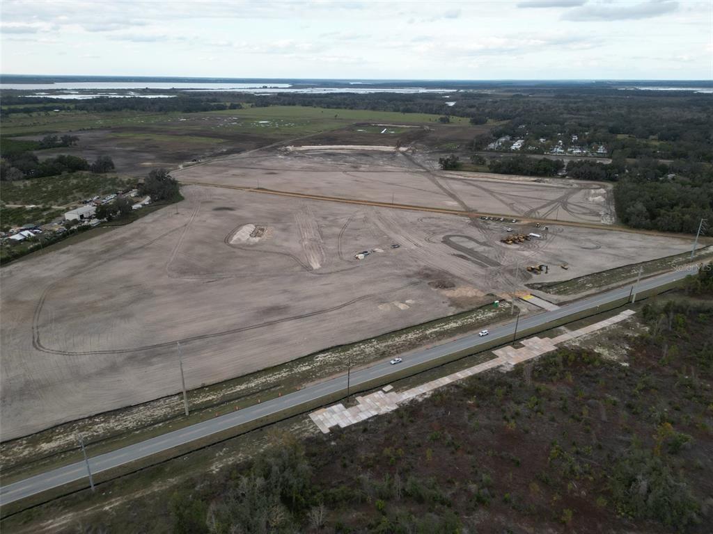 An aerial view shows a large, cleared plot of land adjacent to a paved road — 9915 COUNTY ROAD 44, LEESBURG, FL