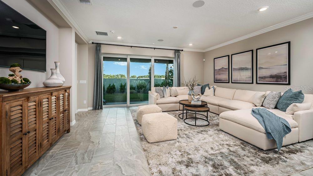 A living room features a large sectional sofa, a wooden cabinet, and sliding glass doors — 6929 PRAIRIE OAK WAY, NOKOMIS, FL