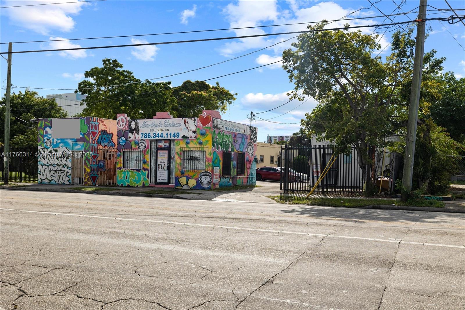 A colorful, graffiti-covered commercial building sits on a street corner with a fenced parking area — 660,662,664 NW 29th St, Miami FL 33127, MIAMI, FL