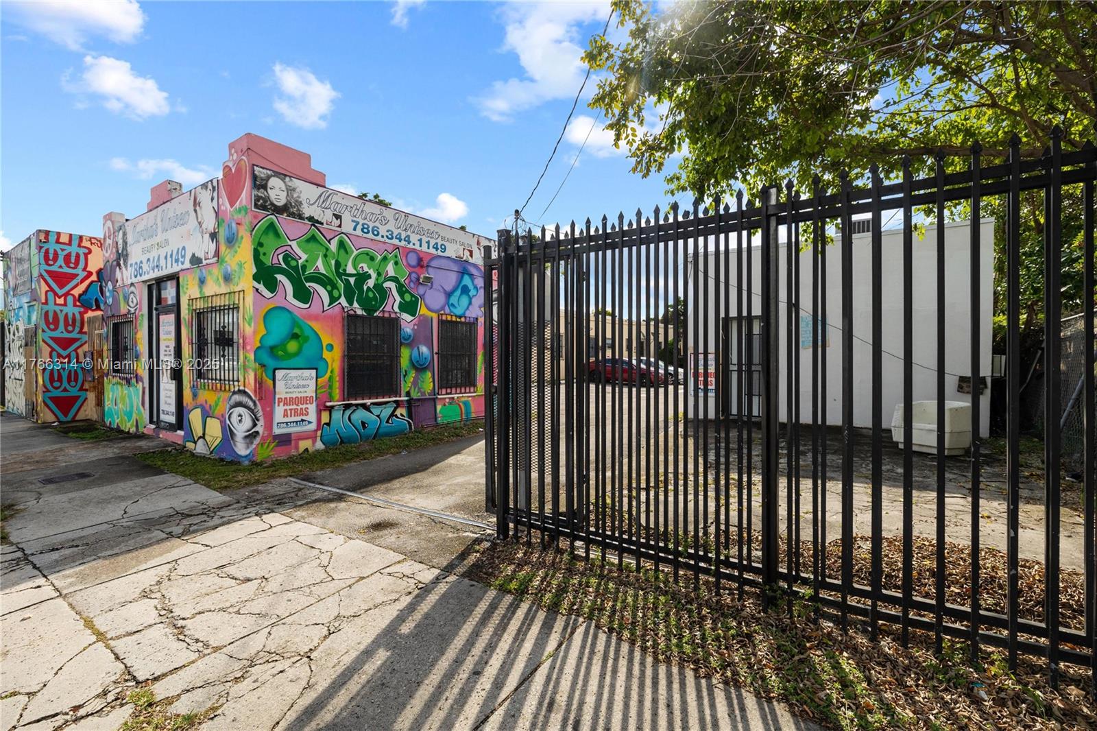 A brightly painted building with graffiti stands next to a fenced parking lot — 660,662,664 NW 29th St, Miami FL 33127, MIAMI, FL