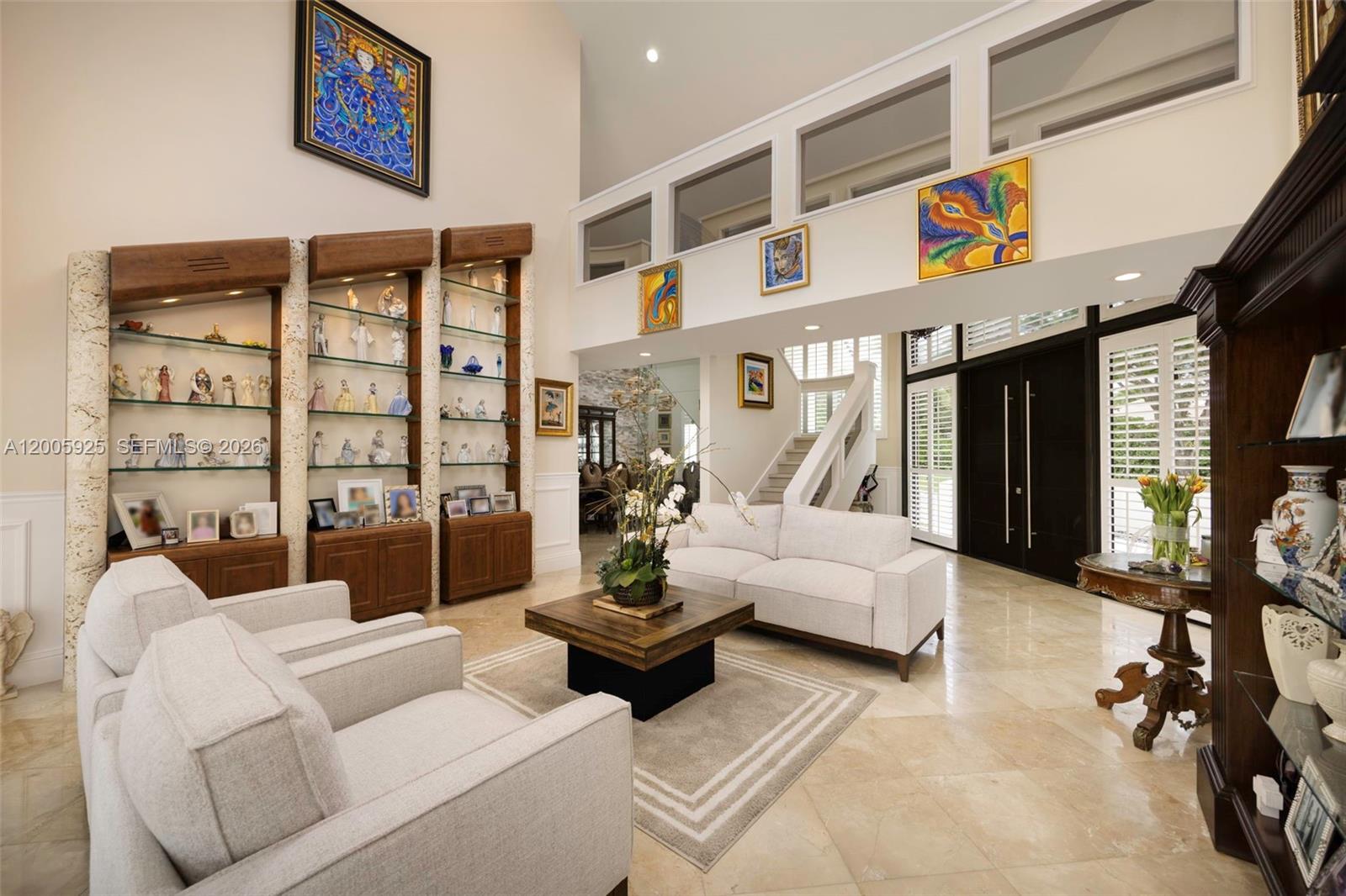 A bright living room features high ceilings, built-in display shelving, and light-colored tile flooring — 8841 SW 103rd St, Miami FL 33176, MIAMI, FL