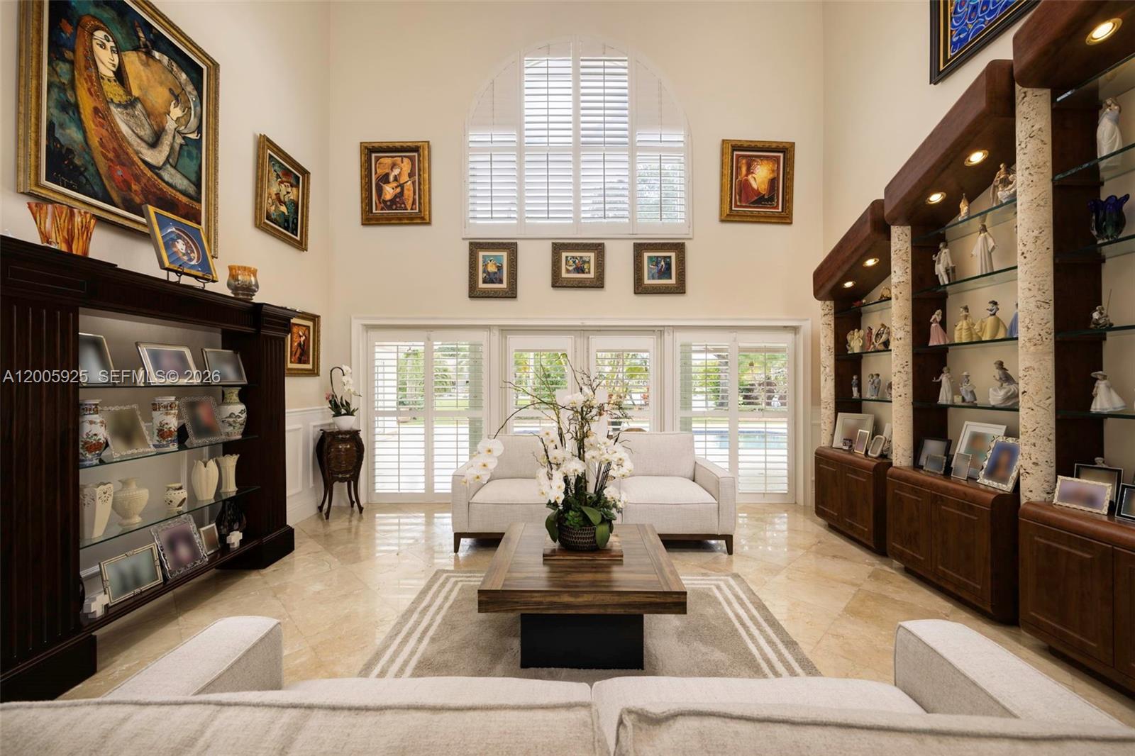 A high-ceilinged living room features tile floors, built-in display shelving, and large shuttered windows — 8841 SW 103rd St, Miami FL 33176, MIAMI, FL
