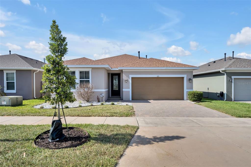 A single-story suburban house with a tan exterior, brown roof, and a two-car garage — 615 CONSERVATION BOULEVARD, GROVELAND, FL
