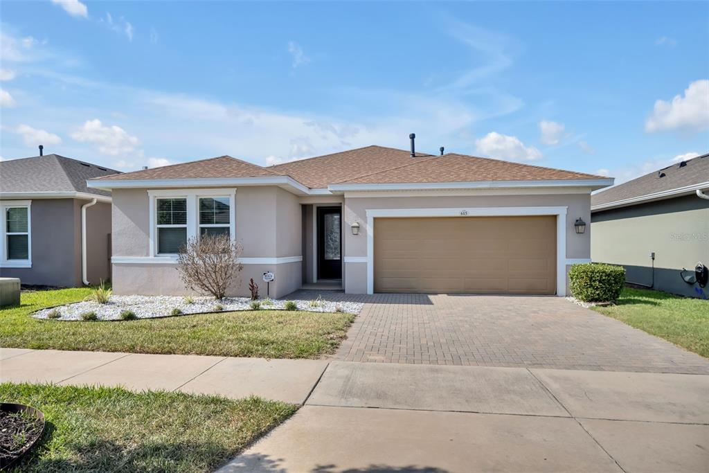 A single-story house with a tan stucco exterior, brown roof, and a two-car garage — 615 CONSERVATION BOULEVARD, GROVELAND, FL
