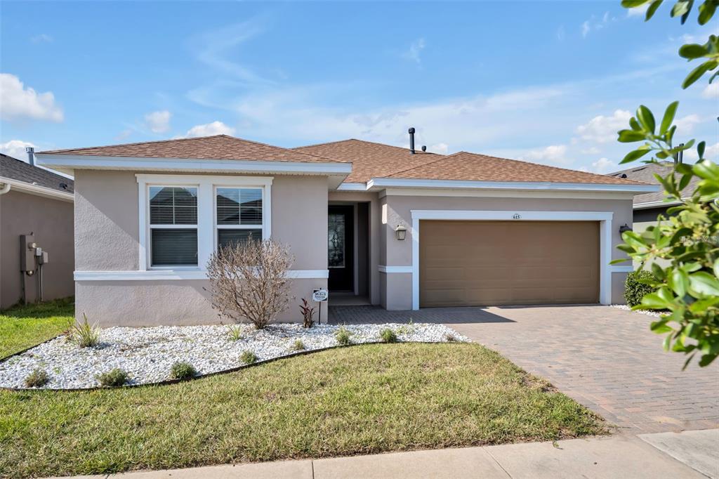 A single-story house with a tan stucco exterior, brown roof, and a two-car garage — 615 CONSERVATION BOULEVARD, GROVELAND, FL
