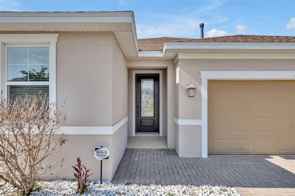 The exterior of a house features a tan stucco facade, a dark front door, and a garage — 615 CONSERVATION BOULEVARD, GROVELAND, FL