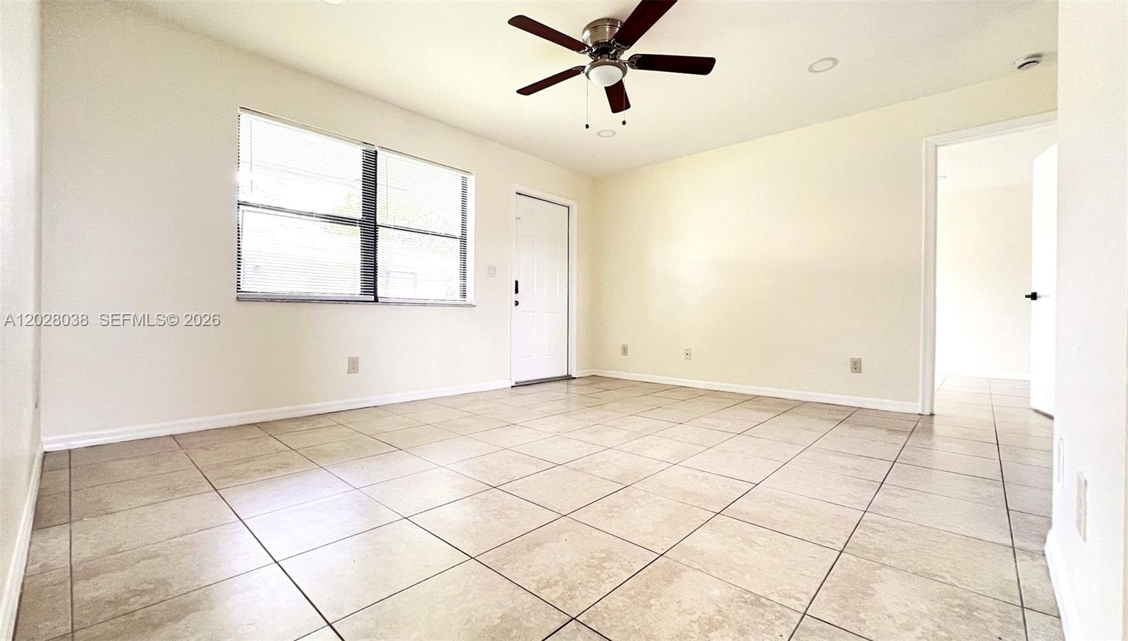 An empty room features light-colored tile flooring, a ceiling fan, and a white door — 5914 Taylor St # 2, Hollywood FL 33021, HOLLYWOOD, FL
