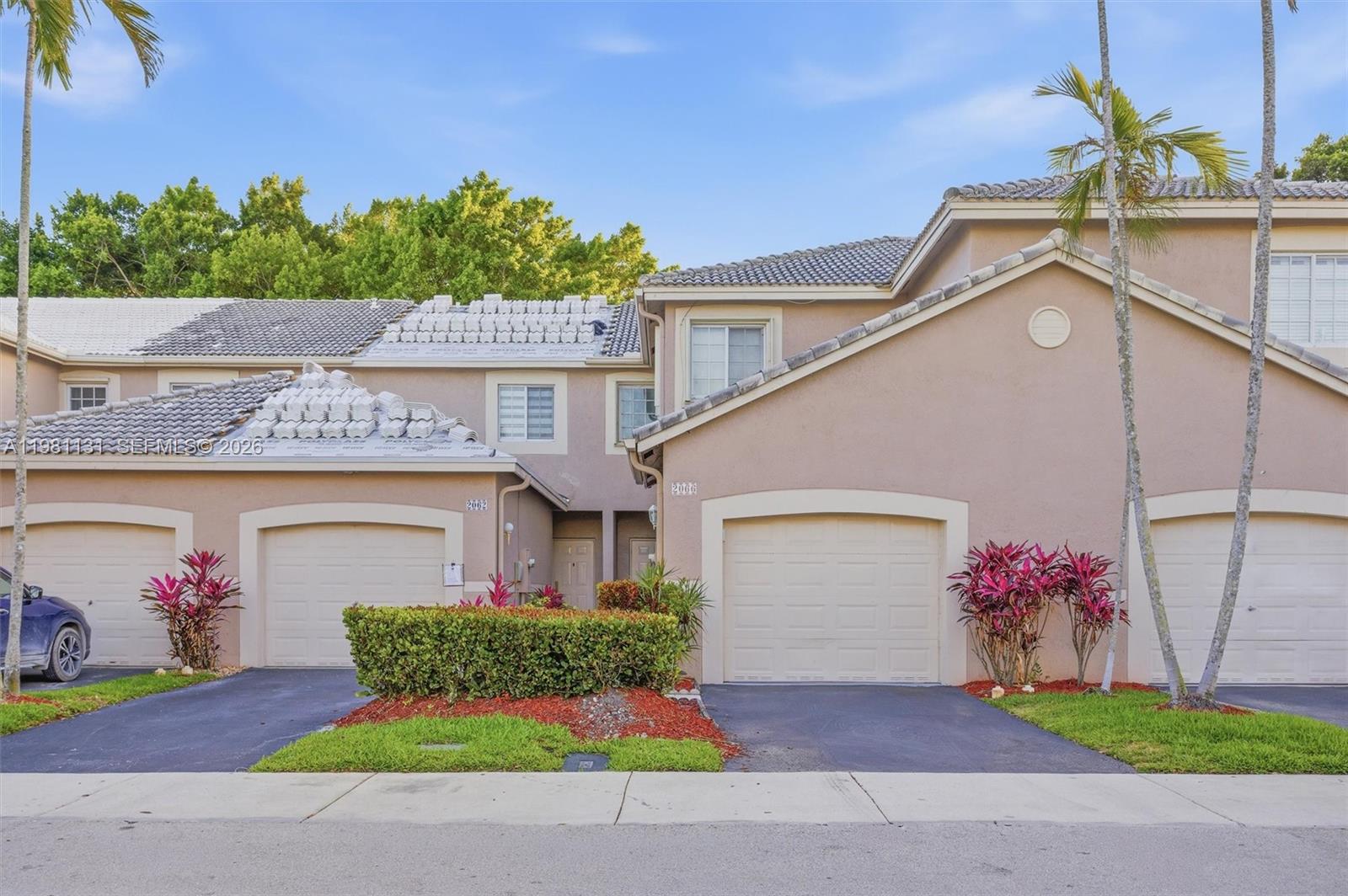 The exterior of a two-story townhouse complex features beige stucco walls and a tiled roof — 2066 Madeira Dr # 2066, Weston FL 33327, WESTON, FL