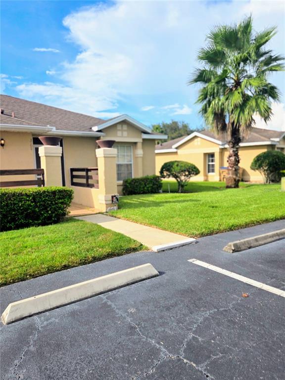 A view of a tan residential building with a palm tree and a parking lot — 3194 SANDY SHORE LANE, KISSIMMEE, FL