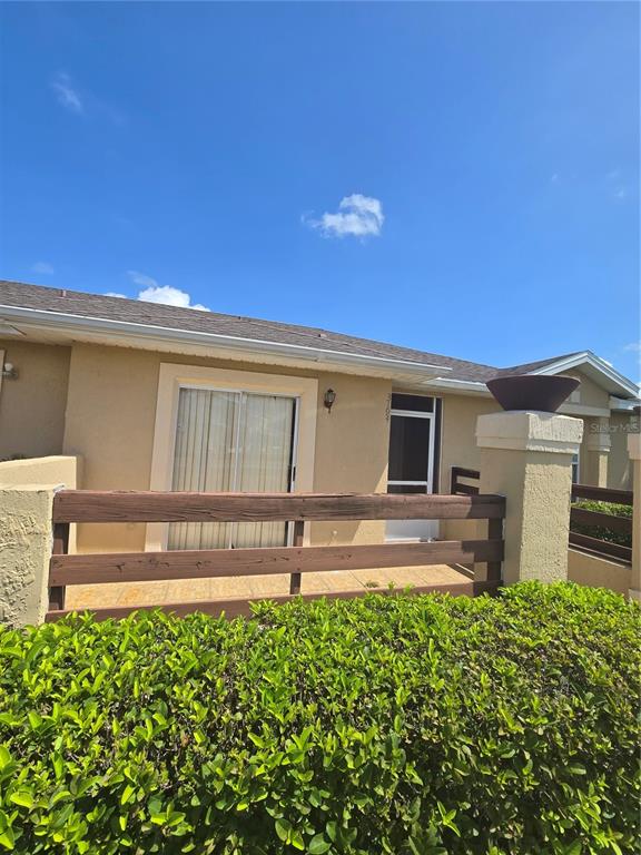 A tan house exterior features a wooden fence, a sliding glass door, and a screen door — 3194 SANDY SHORE LANE, KISSIMMEE, FL