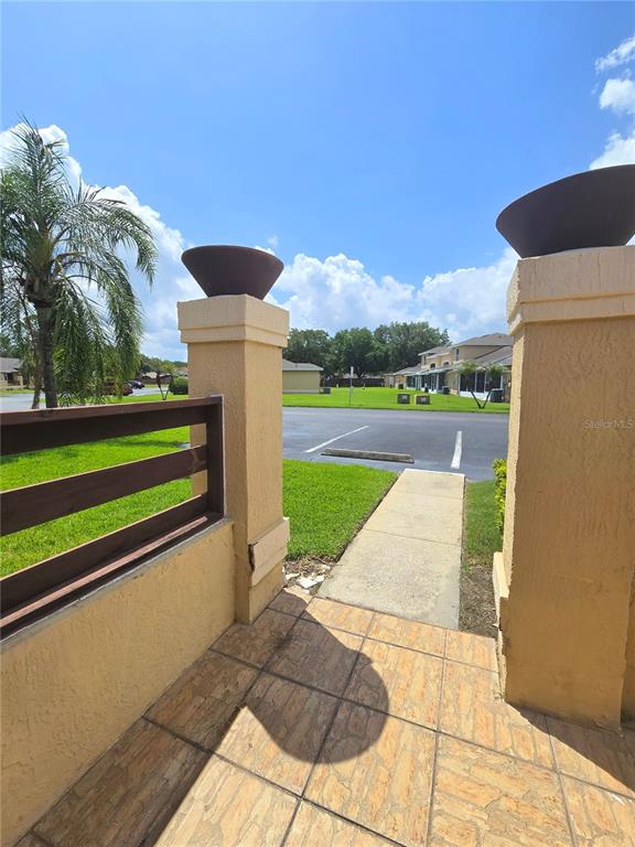 A tiled patio features two stucco pillars with decorative bowls overlooking a parking lot — 3194 SANDY SHORE LANE, KISSIMMEE, FL