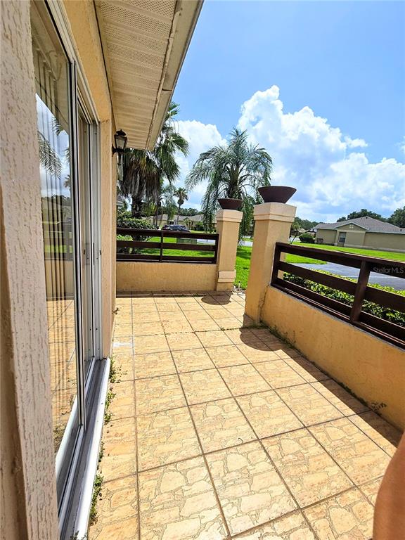 A tiled patio features a low wooden fence and two decorative pillars under a roof — 3194 SANDY SHORE LANE, KISSIMMEE, FL