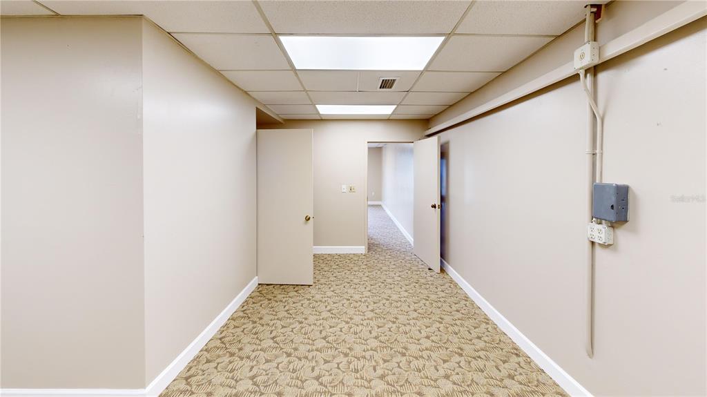 A carpeted hallway leads to an open doorway with beige walls and drop ceiling tiles — 605 NW 53RD AVENUE UNIT A-18, GAINESVILLE, FL