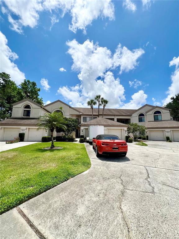 A red car is parked in the driveway of a multi-unit residential building — 3014 RED OAK COURT UNIT 102, PALM HARBOR, FL