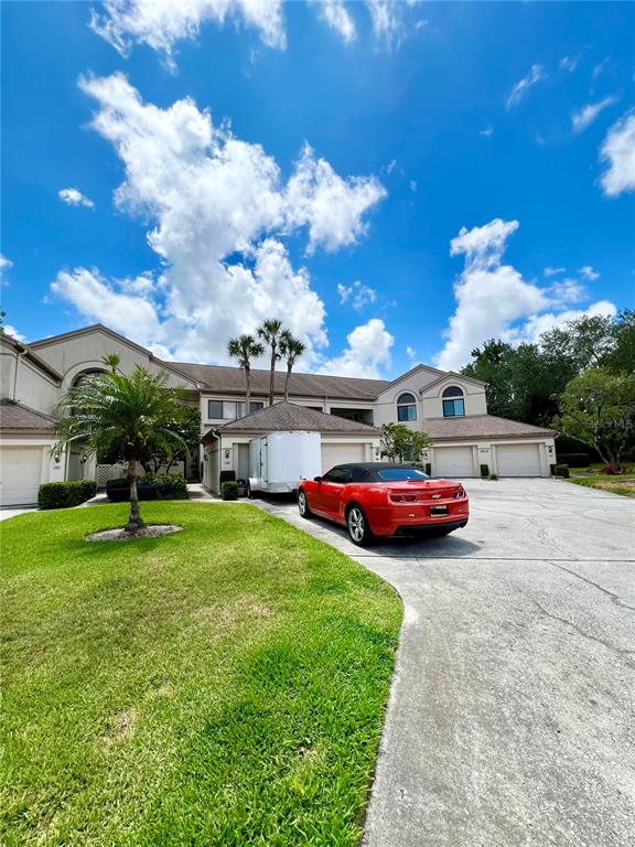 A red convertible is parked in the driveway of a multi-unit residential building — 3014 RED OAK COURT UNIT 102, PALM HARBOR, FL