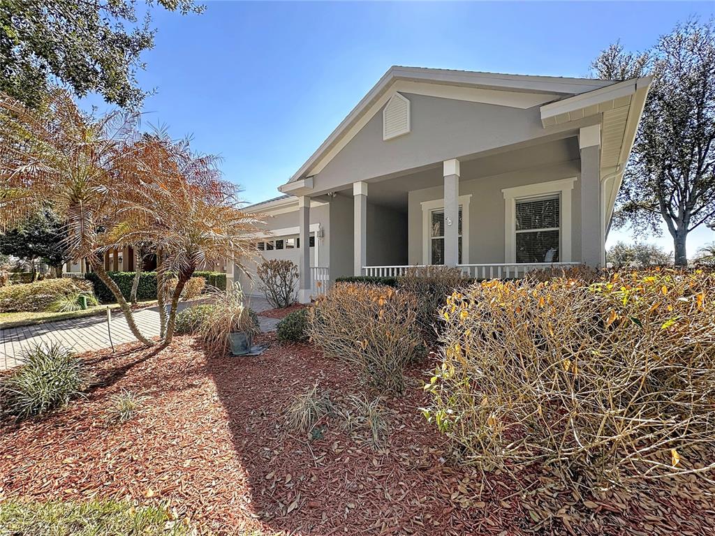 A gray house with a covered front porch, a paved driveway, and landscaped front yard — 146 CREPE MYRTLE DRIVE, GROVELAND, FL